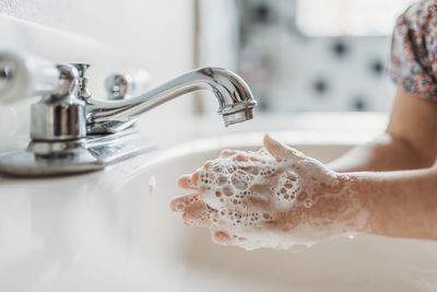 Close up view of young child washing hands with soap in sink