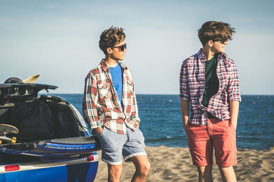 Two young happy teenagers standing at the beach best friends on vacation enjoying summer day outdoor