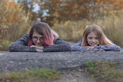 Portrait of sisters lying on road