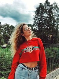 Young woman looking away while standing against trees