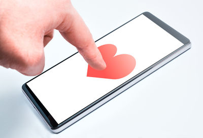 Close-up of hand holding smart phone over white background