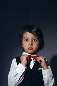 Stylish boy child of four years in the studio on the background in a vest and a red bow tie