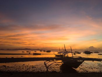 Silhouette boats moored on sea against sky during sunset