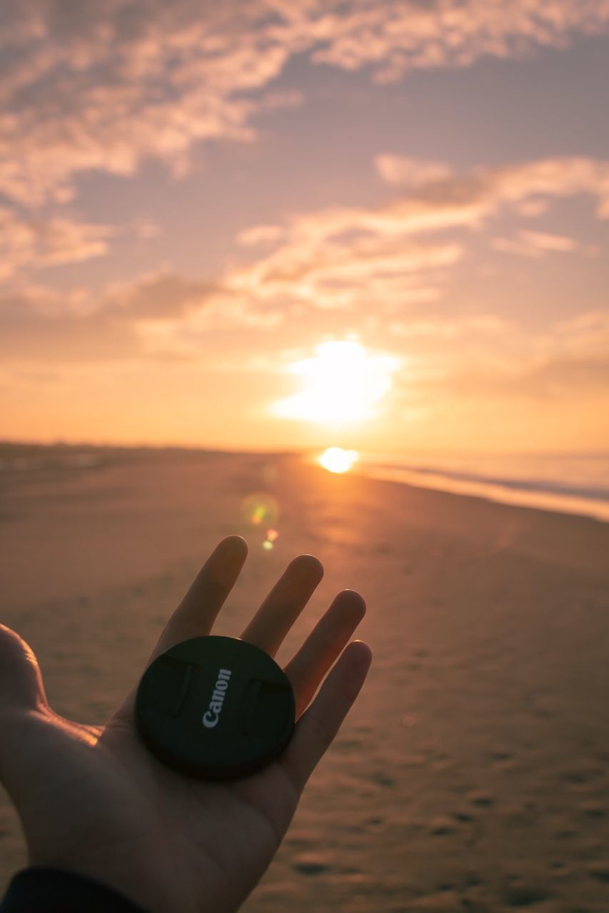 PERSON HAND ON SEA DURING SUNSET