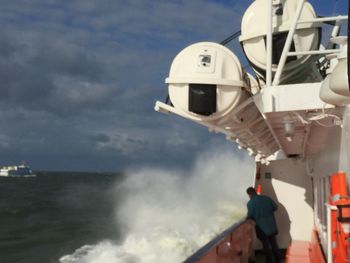 Man by sea against cloudy sky