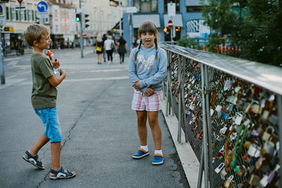 Siblings standing on bridge in city