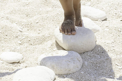 Feet of little girl walking on the white pebbles of a sandy beach