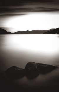 Scenic view of sea by silhouette mountain against sky