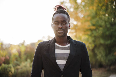 Portrait of young man standing against trees