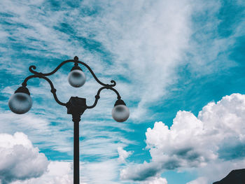 Low angle view of lighting equipment against cloudy sky