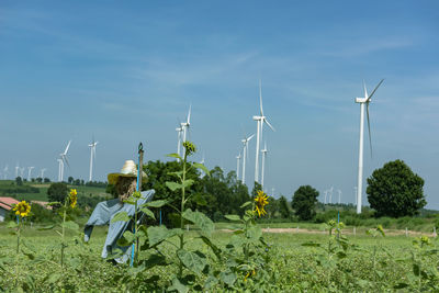 A wind turbine standing in a field. many more turbines can be seen in the distance.