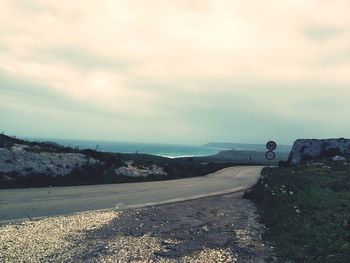 Road passing through city against sky