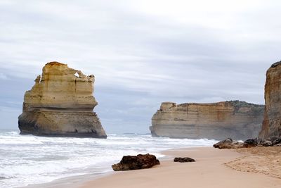 Rock formations on beach against sky