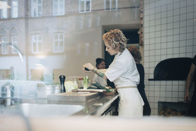 Woman standing by food on table in kitchen