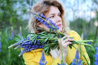 Portrait of beautiful woman holding purple flowering plant