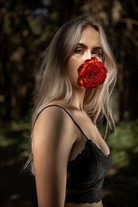 Portrait of young woman holding red flower