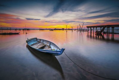 Boat moored on sea against sky during sunset