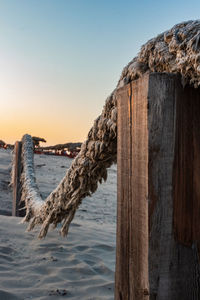 Wooden posts on beach against sky during sunset