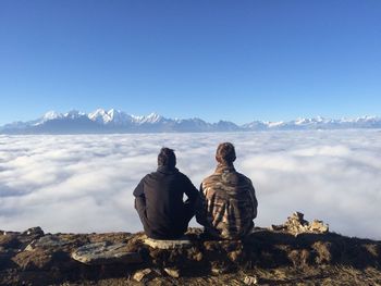 Rear view of people looking at mountain against sky