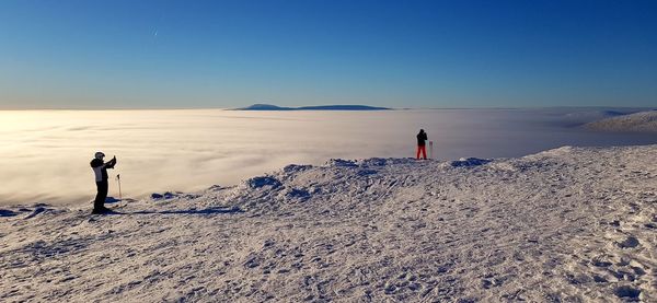 People photographing on landscape against clear sky