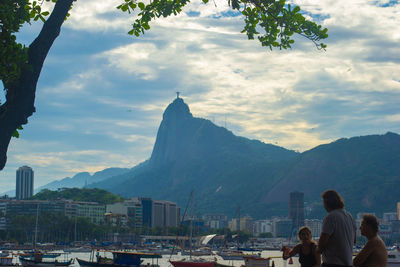 People on boat in mountain against cloudy sky