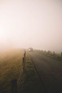 Scenic view of field in foggy weather against sky