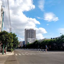 Road by buildings in city against sky