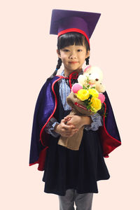 Cute boy holding toy while standing against white background