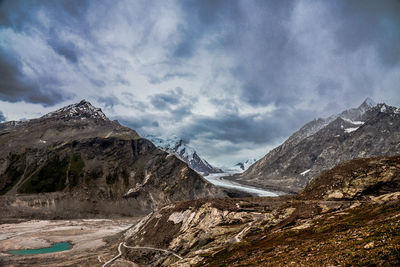 Scenic view of rocky mountains against cloudy sky at drang drung glacier