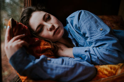 Portrait of young woman lying on bed