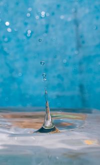 Close-up of drop falling on blue surface