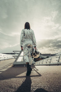 Astronaut holding space helmet walking on footpath