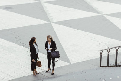 High angle view of female entrepreneurs discussing while standing by staircase