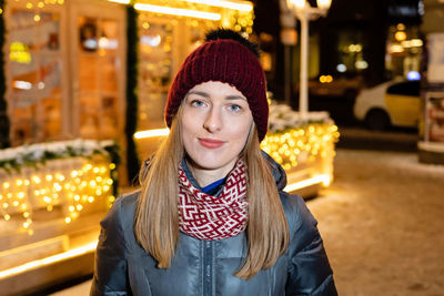 Portrait of smiling young woman in city during christmas