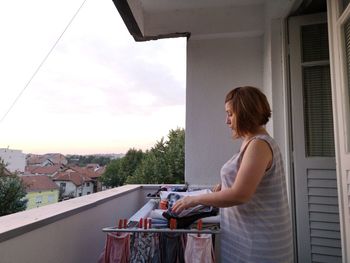 Side view of woman drying laundry on balcony