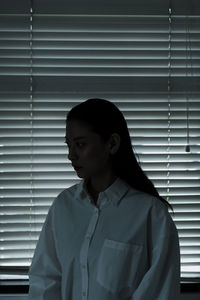 Portrait of young woman looking away against wall