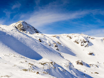 Scenic view of snow covered mountains against blue sky