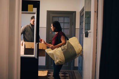 Couple carrying bag and cardboard box while walking in new house