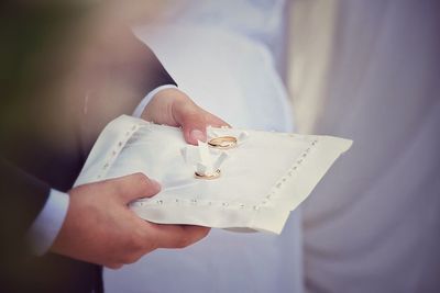 Cropped image of man with rings on fabric during wedding