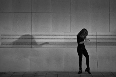 Side view of woman walking against wall