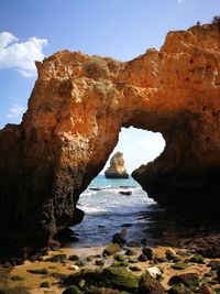 Rock formation on sea shore against sky