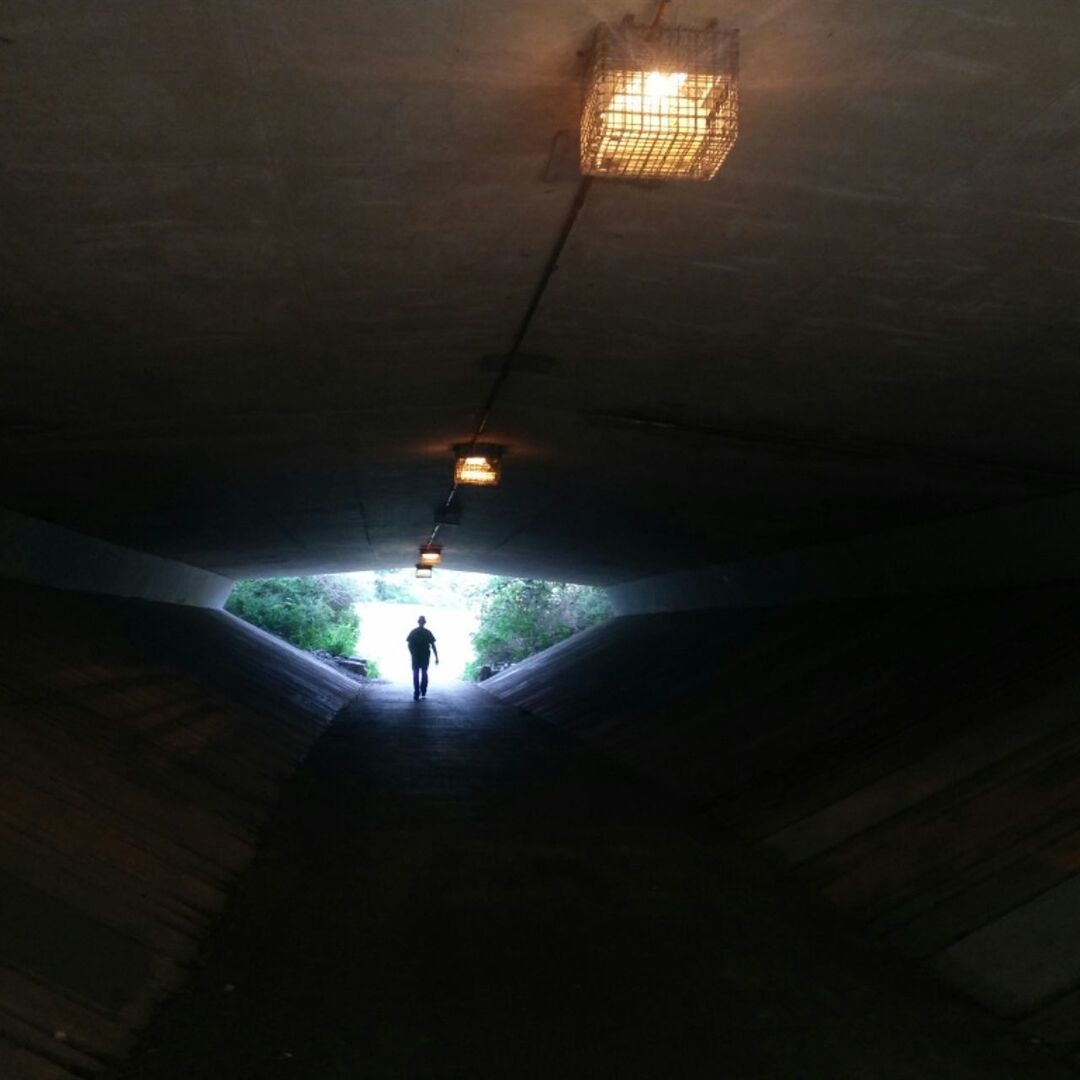 MAN STANDING IN ILLUMINATED TUNNEL