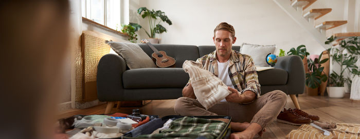 Young woman using mobile phone while sitting on sofa at home