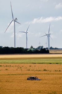 Windmills on field against sky