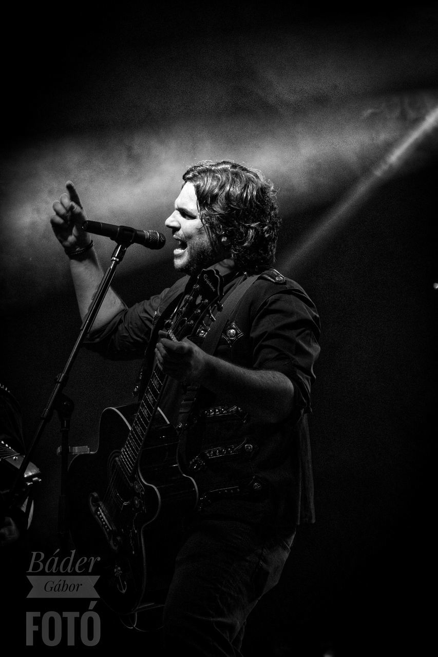 MAN PLAYING GUITAR AT MUSIC CONCERT