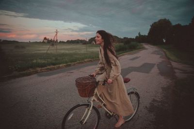 Woman riding bicycle on road against sky