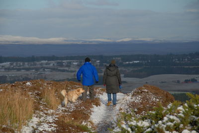 Rear view of dog walking on mountain against sky