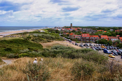 Aerial view of townscape by sea against sky