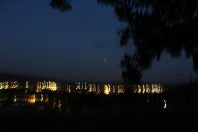 Silhouette trees by lake against sky at night