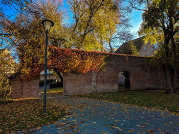 Trees by building against sky during autumn